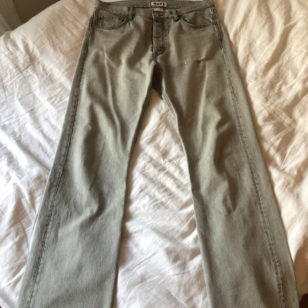 Grå jeans från HOPE i strl 32. Bra skick endast en bältesögla är lös nedtill men kan sys ganska enkelt.   Midja 44,5 cm, innerbenslängd 80, bredd på slutet av benet 24 cm. . Jeans & Byxor.