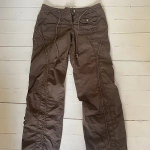 Lågmidjade cargobyxor - Assnygga cargobyxor som jag köpte på Vinted! Var tyvärr för små för mig, annars skulle jag ha dem hela tiden. Snörning både fram och bak. Saknar knappar på bakfickorna men annars inga defekter. Storlek 10 vilket motsvarar 38/40. 