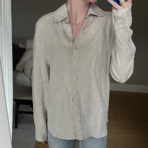 Linneskjorta - Naturfärgad linneskjorta från A-dsgn. 100% linne. Den är något oversize och passar mig som vanligtvis har S/M.