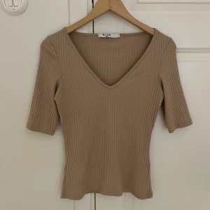 T-shirt  - Beige T-shirt från NAKD. Lite urringad.