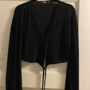 Långärmad omlott croptop - Croppad svart långärmad omlottröja. Mjukt men lite glans/glittrigt material. Aldrig använd. Strl S