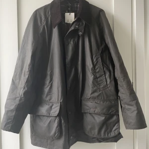 Barbour Bristol NY - Helt ny vaxad jacka från klassiska Barbour. Har endast provat den men insett att modellen inte är för mig. Modellen heter Bristol. Olivgrön. Storlek XL. Lappar och orginalemballage kvar. Perfekt för höst och vår. Tål regn och rusk mycket bra.