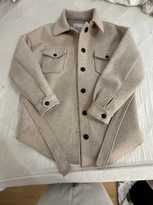 Höst/vårkappa  - Jättefin kappa i färgen beige använd hela hösten men är fortfarande som ny, inga hål märken eller illaluktande dofter, håller värmen och får även fram midjan med hjälp av bandet på kappan😁passar S/M/L