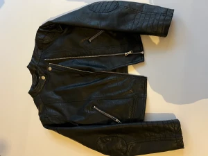 Skinnjacka svart - Använd skinnjacka i färgen svart. Den är i nyskick. Fina detaljer vid armbågarna. 
