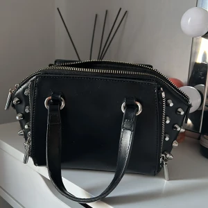 Väska - Fin handväska som passar till alla outfits. Den har tre fack, ett stort och två små på sidorna. Axelrem följer med :) 