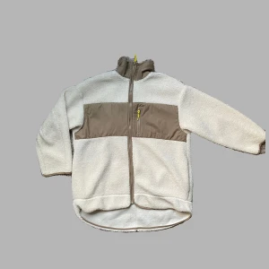Teddyfleece  - Säljer min teddyfleece från H&M som är perfekt att ha under jackan nu när det är lite kallare. Säljer på grund av har en liknande. Den är i krämvit med ljusbruna/beige detaljer och gula dragkedjor. 100% polyester. S men passar även M.