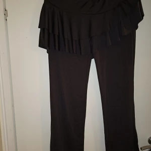 Byxor med kjol - Kjol och byxa i ett, i stretchigt polyester-material. Kjolen är ca 32 cm på det längsta stället, Obs på att kjolen är asymmetrisk. Byxorna är 100cm från midja till fot. Aldrig använda.
