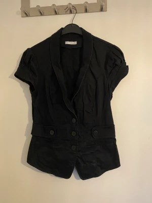 Figursydd kostymväst med korsettstuk - Kostymväst/kavaj som sitter figursytt med coola knappar och snygg krage, inga tecken på användning 