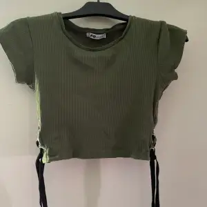 Mörkt grön tröja med knytning i sidorna 