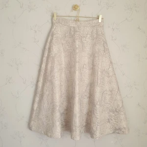 Beige vit Glittrig Kjol - 💕FÖRST TILL KVARN💕 En jättefin kjol som är A-linje skuren med fin detaljerat tyg. Krämvit i strl 34 men passar en liten 36. Dags att släppa den🥲💔 Gulligt att ha till våren, en fest. Studenten skulle den nog också passa. Vill bli av med ASAP! 180+ frakt