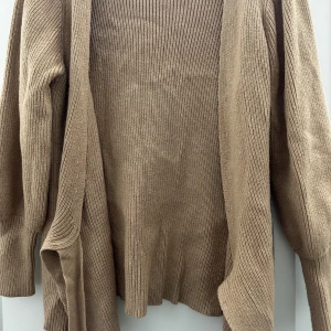 Stickad kofta - Beige/brun stickad kofta/kardigan som går precis till rumpan. Väldigt fina pösiga armar. Aldrig använd.