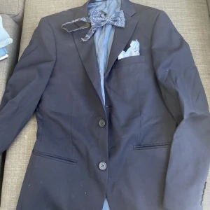 Mörkblå kavaj - Jag har använt den 2 gånger och det var på 9ans bal samt studenten.  Den är tvättad efter balen och sen efter studenten och nu är den för liten för mig. Du får med både fluga och en duk Storlek 44 slim fit. Jag tvättar och stryker den innan leverans. 
