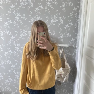 Gul hoodie - Relativt bra skick. Mjuk i ett ganska tunt tyg. Skriv gärna om frågor eller om ni vill ha fler bilder. Defekt: har en liten fläck på luvan