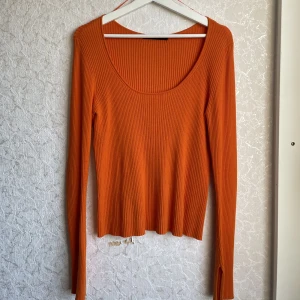 Långärmad tröja med slits - Orange ribbad långärmad tröja från Bik Bok i storlek Large. Fin skurning och en slits vid ärmarna som är en mycket fin detalj. Mjukt material. Säljer pga den aldrig kommer till användning för mig tyvärr.  (Samfrakt: flera produkter i samma frakt)