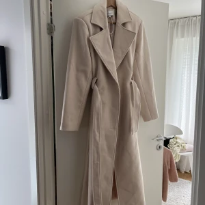 BEIGE KAPPA NAKD ANGELICA BLICK OANVÄND - Stl 36  Beige lång kappa från NAKD x Angelica Blick  Lite oversized 