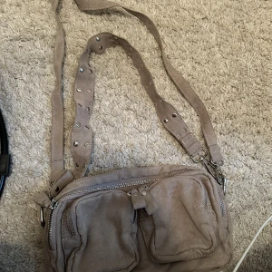 Cross-body väska H - Populär Oanvänd cross body väska från Gina tricot, medföljer långt band så du kan ha den som ”vanlig” väska. 