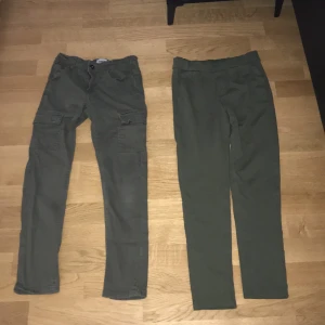 2 par gröna byxor  - 1 byxa är cargo jeans, andra paret är en typ av mjukisbyxor. Man kan tighta till båda byxorna i inre sidan av byxorna vid höften. Den ena byxan kommer med fickor på sidan, den andra kommer med fickor bakom men bara som dekoration.