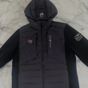 Sail racing Antarctica hybridhood/svart - En stil ren snygg bekväm jacka,passar till vinter,vår och höst. Köpt för 3500 kr och den går inte få tag i mer. Skick 9,5/10 vill ni har mer foton så är det bara att skriva 