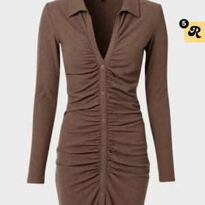 Brun Klänning - Brun klänning med knappar från Nelly. Aldrig använd. Lappar sitter kvar på klänningen.