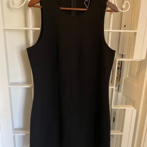 Svart klänning från Monki - Rejält tyg. Helt ny, aldrig använd. Storlek 44.  Alla mått i centimeter. Byst: 98 Midja: 96 Längd: 90 Axel till axel: 33  63 % polyester 33 % viskos 4 % elastan.