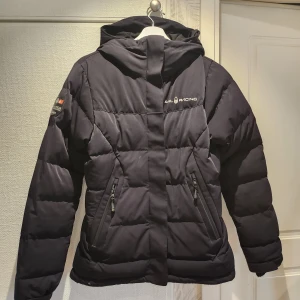 Sail racing  - Vinterjacka i dun. Storlek Medium  Dam modell.  Finns en liten reva längst ner som kan limmas om man vill, men ingenting som förstör funktionen och knappt synlig vid användning.  