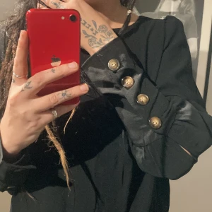 Svart Blus - Jättefint svart blus med lite puffigare ärmar som smalnar av med knäppning nere. Samma knäppning i ryggen. Aldrig använd men storlekslappen är tyvärr borta.  Jag på bilden är strl. S-M.