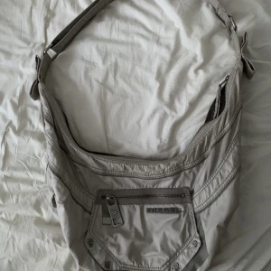 Diesel axelremsväska - Cool och unik axelremsväska/crossbody väska från Diesel. Finns några få skiftningar i färgen på tyget men annars är den i superfint begagnat skick! 