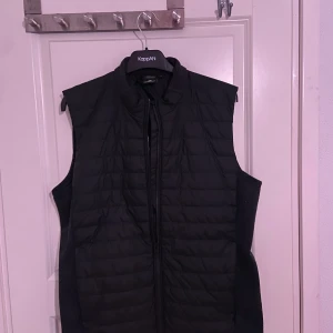 Didriksons väst - Svart väst från Didriksons i Storlek L. Anvånd ett fåtal gånger så den är som ny. Stickat på ryggen och framtill ser den ut som en vanlig väst. 