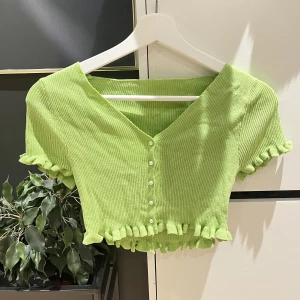 Grön topp - Fin grön topp med vita pärlor som knappar.  Strl: S Skick: bra skick, aldrig använd. 