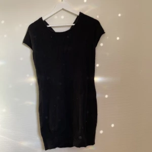 Stickad klänning  - En superfin svart stickad klänning i bland annat angora och ull. Klänningen har en cutout detalj på baksidan där man knyter med en rosett. Klänningen har ett litet hål på ena axeln kan skicka bild om det efterfrågas.