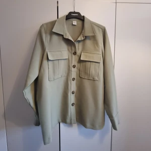 Ljus militärgrön skortjacka Ellos - Ljus militärgrön skjortjacka från Ellos. Med knytning i midjan. Storlek 38