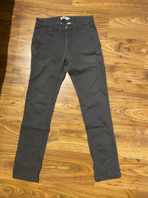 Chinos - Snygga mörkgråa chinos från NNO7. Storlek 30-32. Bra skick och väldigt annvändbara och lämpliga till vardags. Vid intresse av alla tre färger skriv till mig så kan vi lösa en bra deal. 
