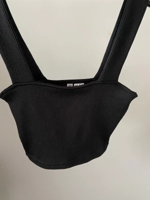 Svart Croptop - Svart croptop från H&M. Ribbat stretchigt material. Använd ändast 1 gång så den är i fint skick.