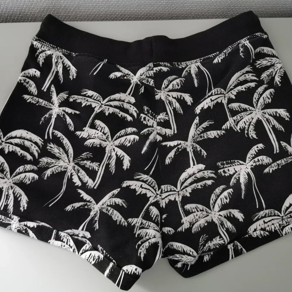 Sköna mjukisshorts med snörning som är svarta med vita palmer på. Fint skick! 35% bomull och 65% polyester.. Shorts.