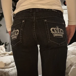 Y2k svart-gråa lowrise jeans  - Skitcoola lowrise jeans med kronor på bakfickorna :) Säljer då de inte passar min stil lika bra.