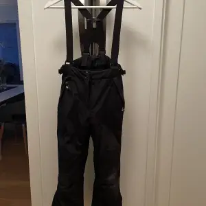 Skidbyxor med avtagbara hängslen, 2 fickor och reflex bak på ena benet.