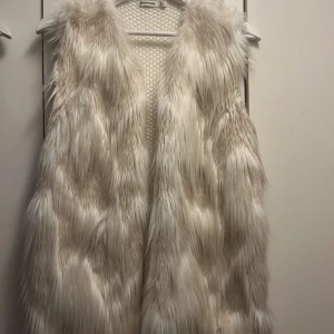 Stickad väst med fuskpäls - Fin väst med fuskpäls framtill och virkat mönster baktill. Superfint skick! Storlek L 
