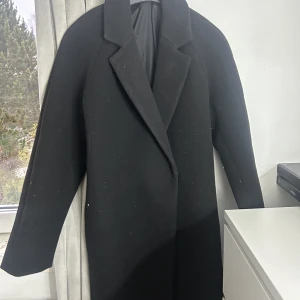 Svart kappa  - Säljer denna super fina kappa från hm i storlek xs men passar absolut en S då den är lite stor.den är nästan helt ny så där av priset.  Den har lite ludd på sig så det är inga defekter utan det går att ta bort😊