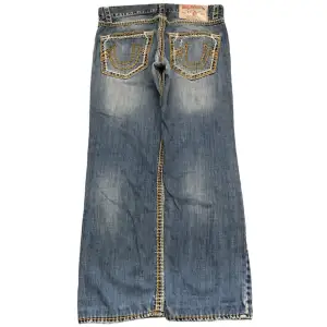 Straight/baggy True religion jeans i modellen Ricky super QT. Storlek 33x32, benöppning 21cm. Lagningar på insidan av jeansen men inget som märks från utsidan. 