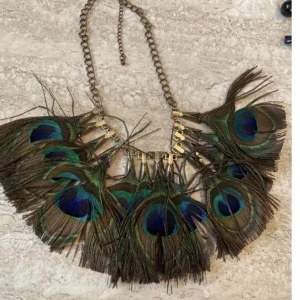 Påfågel fjädrar halsband  - Halsband med rad av påfågelfjädrar. I bra skick!  Finns att hämta i Stockholm! Hör av dig om du har någon fundering och titta gärna in mina andra annonser.