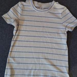 En vit,svart och ljusgul ribbad T-shirt för barn! Använd men i god skick. Från Lindex. Storlek: 128 7-8Y 