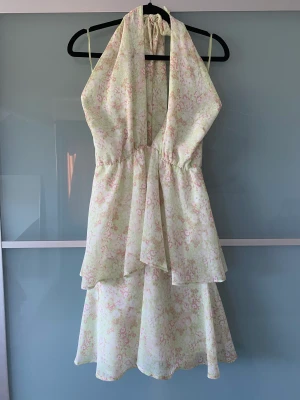 Blommig klänning  - Söt blommig klänning utan rygg med knyte i nacken.