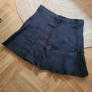 Kort svart kjol plisserad m lagda veck. Är som en stl.S/M : midjemått runt om: ca 72cm, kjollängd ca 37cm. Ny! Aldrig använd då storleken ej passade.