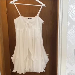 Vit klänning  - Vit somrig klänning☀️Klänningen har band på framsidan som går att knyta hur man vill. På andra bilden har jag gjort en rosett🎀 Klänningen är i storlek 38. Bra skick.