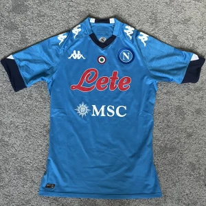 Napoli fotbollströja - En äkta Napoli tröja från 20/21 säsongen. Det är dessutom spelarversion som är den sorts material på tröjan som spelarna har på sig under matcherna. Tröjan är knappt använd och är därmed i lysande skick. 