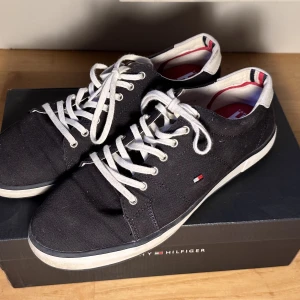 Canvas Skor Tommy Hilfiger - Ett par marineblå Canvas skor från Tommy Hilfiger. Använda en sommar. Hela men lite smutsiga på sulan. Köpta för 699