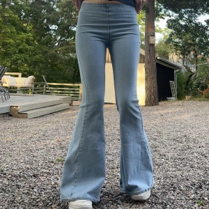 Utsvängda 70-tals jeans -  Utsvängda ljusblå 70-tals jeans med vanlig midja. De sitter tight och har ett resårband i midjan. Större utsvängning på 34 cm tvärs över. Jag är 170 cm på bilden. Finns några tecken på användning men är i bra skick. ☺️