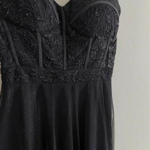 Balklänning från Dressroom linné✨ - Säljer min balklänning. Den är i färgen svart och har en korsettliknande överdel! Den är täckt med glitter och små detaljer. Den är lite längre bak alltså är det ett litet släp. Stl 34/36, insydd men går att sprätta upp🤍Köparen står för frakt!