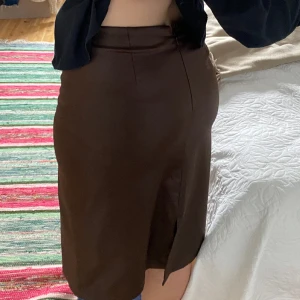 Brun kjol - Brun kjol i glansigt material med slits bak