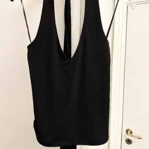 Svart topp - Svart U rungad topp från Bikbok som man knyter i nacken med öppen rygg. Aldrig använd och lappen sitter kvar. 